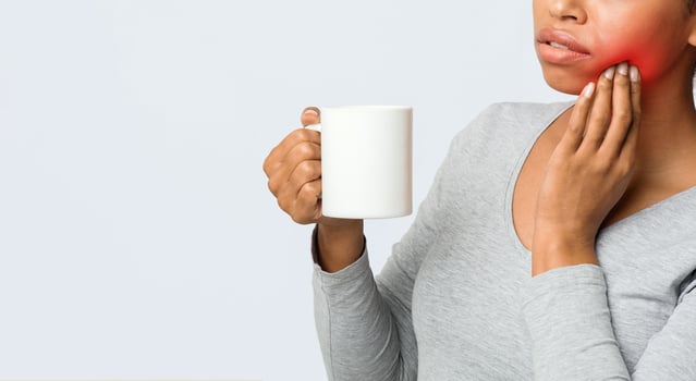 Sensitive teeth. Black girl drinking coffee and touching her cheek, close up, copy space photo