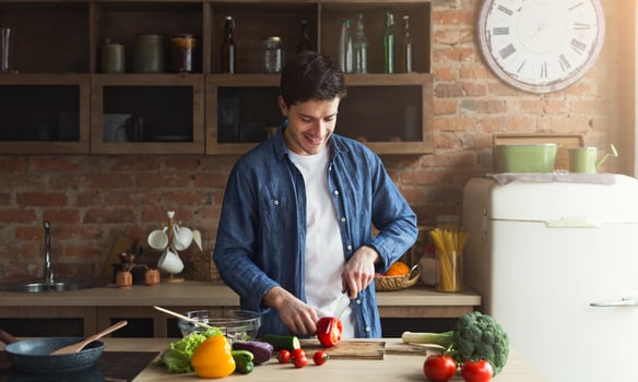 Man cooking delicious and healthy food in the loft kitchen at home on sunny day. Preparing vegetable salad. photo