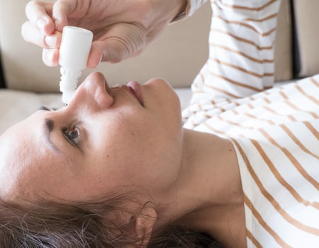 Woman dripping into her eyes with antibacterial drops closeup photo