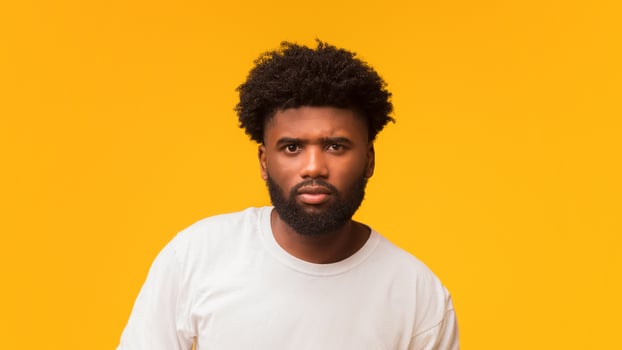 Serious afro man posing over orange studio background photo