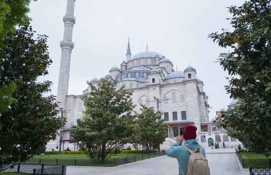 A male tourist takes a photo of the Fatih Mosque in Istanbul, Turkey as a keepsake.