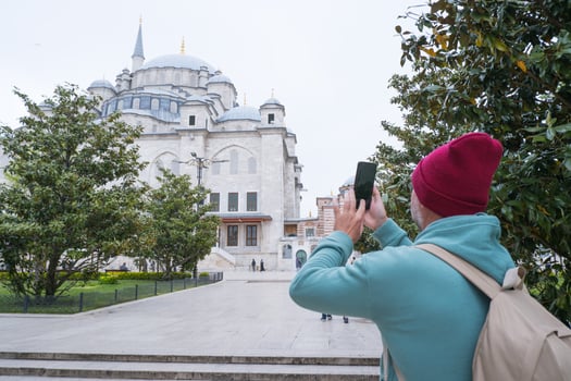 A male tourist takes a photo of the Fatih Mosque in Istanbul, Turkey as a keepsake.