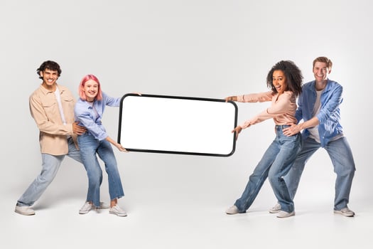 Four young adults, two women and two men, are holding a large smartphone with blank screen in front of a white background. photo