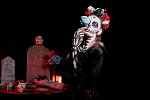 Woman with eyes closed posing with flower for Day of the Dead event to remember the deceased, celebrating their memory. Girl holding blue rose for holiday of remembrance for those who have passed photo