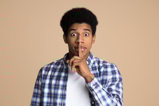 Just don't speak. Teen making hush gesture over light background photo