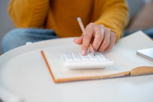A woman using a calculator to manage her household expenses and calculate her monthly savings. photo