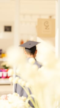 Blurred Graduate in Cap and Gown with White Flowers in Foreground photo