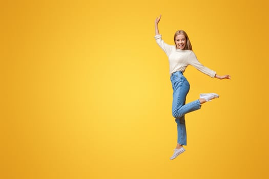 Carefree youth. Happy young girl jumping on air and smiling over orange background photo