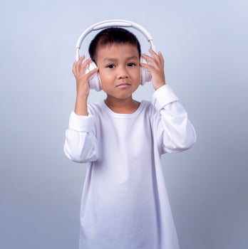 Asian cute boy wearing white and wearing white headphones on his head, Boy standing on white background, Lifestyle of a boy on a white background. photo