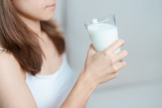Milk drink and Daily Routine concept. Young woman Drinking milk with high calcium and nutrition at home, woman holding soy milk on glass with protein. Healthy, wellness and happy lifestyle photo