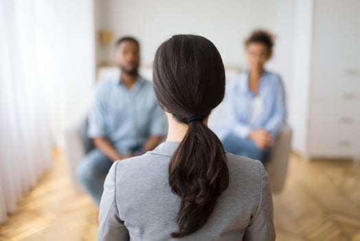 Couples Therapy Session. Counselor Listening To Afro Husband And Wife Sharing Problems In Office. Back View, Selective Focus, Copy Space photo