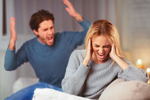 Abusive Relationship. Aggressive Man Shouting At Desperate Woman Sitting On Sofa At Home. Selective Focus photo