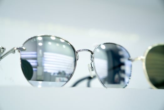 Close-up of round sunglasses with reflective silver lenses, highlighting stylish sleek modern design and metallic frames, fashion-forward accessories, minimalist display, retail ambiance photo