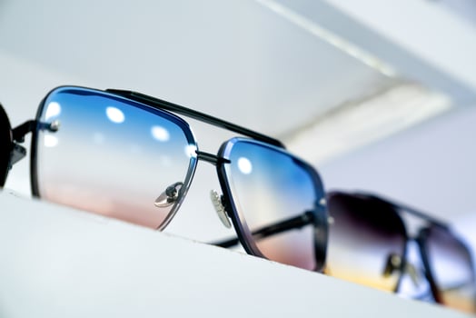 Close-up of stylish sunglasses with gradient lenses on display, modern eyewear design, reflecting vibrant colors, sleek frames, fashion-forward accessories, showcasing trendy style in retail setting photo