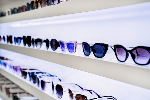 White shelves filled with sunglasses in various styles and dark lens hues, creating organized eyewear selection, fashion-focused retail atmosphere, inviting shoppers, side view. photo