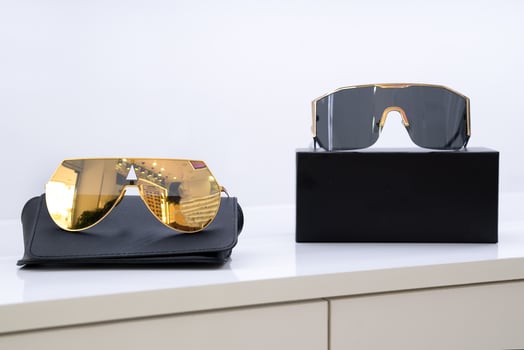 Premium sunglasses with gold and black lenses on black sleek cases, fashion-forward design, minimalistic and modern look, luxury accessories, retail presentation of stylish eyewear photo