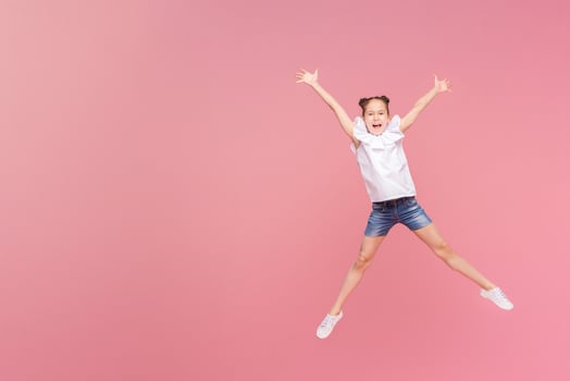 Funny little girl laughing, jumping on pink background and enjoying life photo