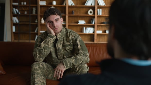 Sad client Caucasian thoughtful depressed man military soldier male officer in combat uniform guy defender holding head suffering depression PTSD stress speaking counselor psychologist at office room photo