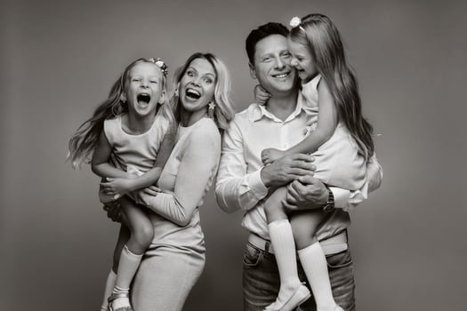 Happy parents hold their children in their arms and smile on a yellow background. an emotional family of four photo