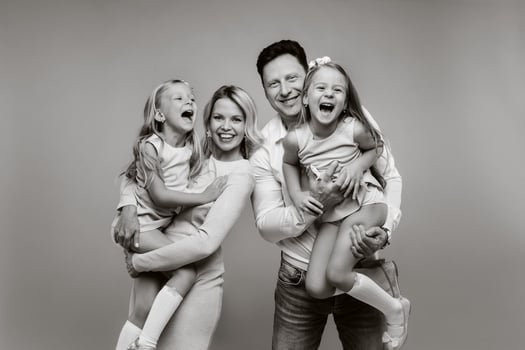 Happy parents hold their children in their arms and smile on a yellow background. an emotional family of four photo