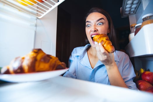 Ripped off diet. Hungry woman eating croissant from fridge, view from inside photo