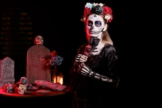 Woman dressed in Day of the Dead costume with flower wreath on head celebrating Dia de los Muertos. Girl wearing skeleton makeup promoting Mexican culture during Halloween, holding black roses photo