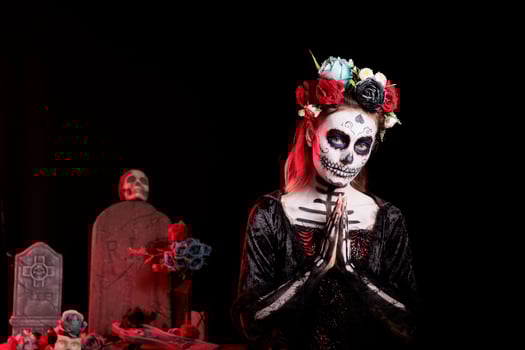 Woman doing praying hand gesture at Day of the Dead event to remember the deceased. Spiritual lady doing religious gesturing during Mexican holiday of remembrance for those who have passed photo