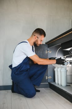 Plumber working install new cartridge for cold water filter in white kitchen photo