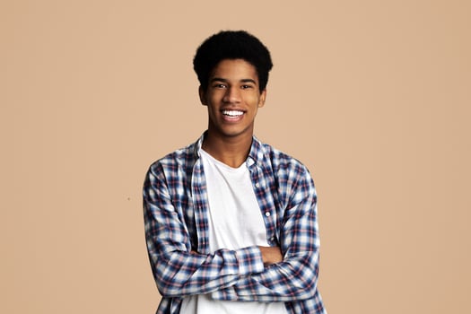 Happy teen guy posing with crossed hands and smiling to camera over white background photo