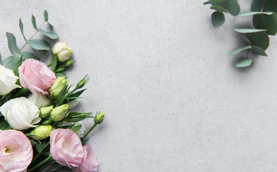 Delicate arrangement of mixed flowers and eucalyptus leaves on a light grey surface photo