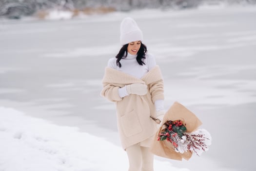 A girl in a beige cardigan and winter flowers walks in nature in the snowy season. Winter weather photo