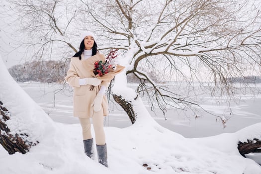 A girl in a beige cardigan and winter flowers walks in nature in the snowy season. Winter weather photo