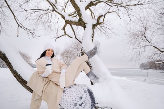A beautiful girl with a beige cardigan and a white hat enjoying drinking tea in a snowy winter forest near a lake photo