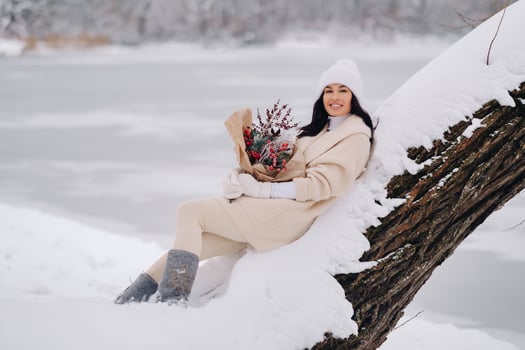 A girl in a beige cardigan and winter flowers walks in nature in the snowy season. Winter weather photo