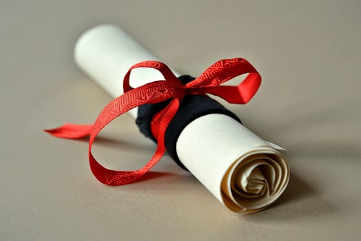 Diploma tied with a red ribbon lying on a wooden table photo