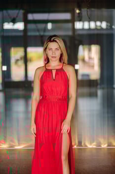 A girl in a red dress moves in a dance meditating indoors . Dynamic dance photo