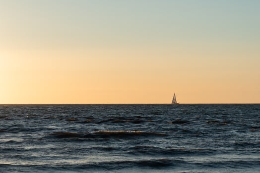 Sailing boat on the horizon during sunset photo