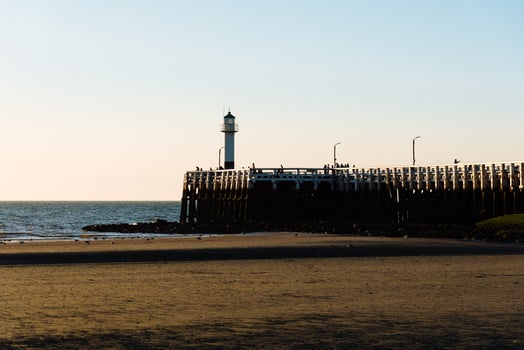People admiring sunset on the pier with a lighthouse photo