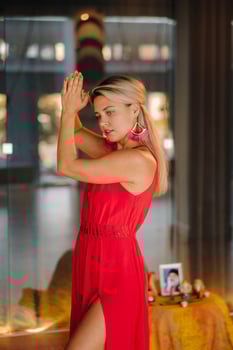 A girl in a red dress moves in a dance meditating indoors . Dynamic dance photo