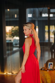 A girl in a red dress moves in a dance meditating indoors . Dynamic dance photo