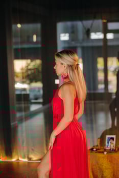 A girl in a red dress moves in a dance meditating indoors . Dynamic dance photo
