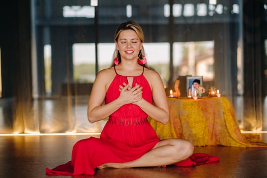 Meditation and concentration. a woman in a red dress sitting on the floor is practicing medicine indoors . Calm and relaxation photo