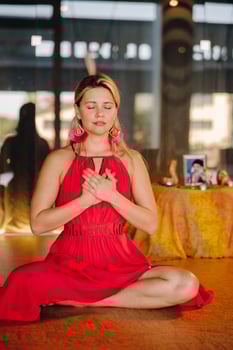 Meditation and concentration. a woman in a red dress, sitting on the floor with her eyes closed, is practicing medicine indoors. Peace and relaxation photo