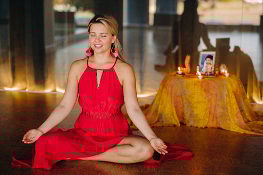 Meditation and concentration. a woman in a red dress, sitting on the floor with her eyes closed, is practicing medicine indoors. Peace and relaxation photo