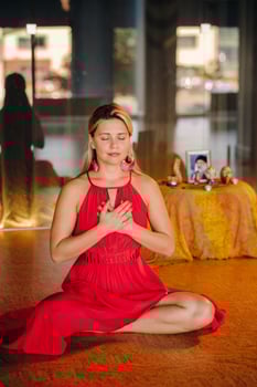 Meditation and concentration. a woman in a red dress, sitting on the floor with her eyes closed, is practicing medicine indoors. Peace and relaxation photo
