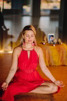 Meditation and concentration. a woman in a red dress, sitting on the floor with her eyes closed, is practicing medicine indoors. Peace and relaxation photo