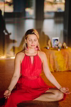 Meditation and concentration. a woman in a red dress, sitting on the floor with her eyes closed, is practicing medicine indoors. Peace and relaxation photo