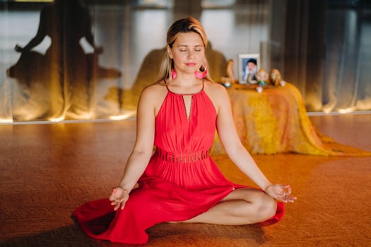 Meditation and concentration. a woman in a red dress, sitting on the floor with her eyes closed, is practicing medicine indoors. Peace and relaxation photo