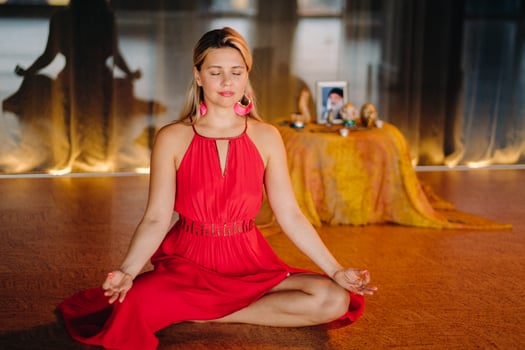 Meditation and concentration. a woman in a red dress, sitting on the floor with her eyes closed, is practicing medicine indoors. Peace and relaxation photo
