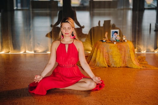 Meditation and concentration. a woman in a red dress, sitting on the floor with her eyes closed, is practicing medicine indoors. Peace and relaxation photo